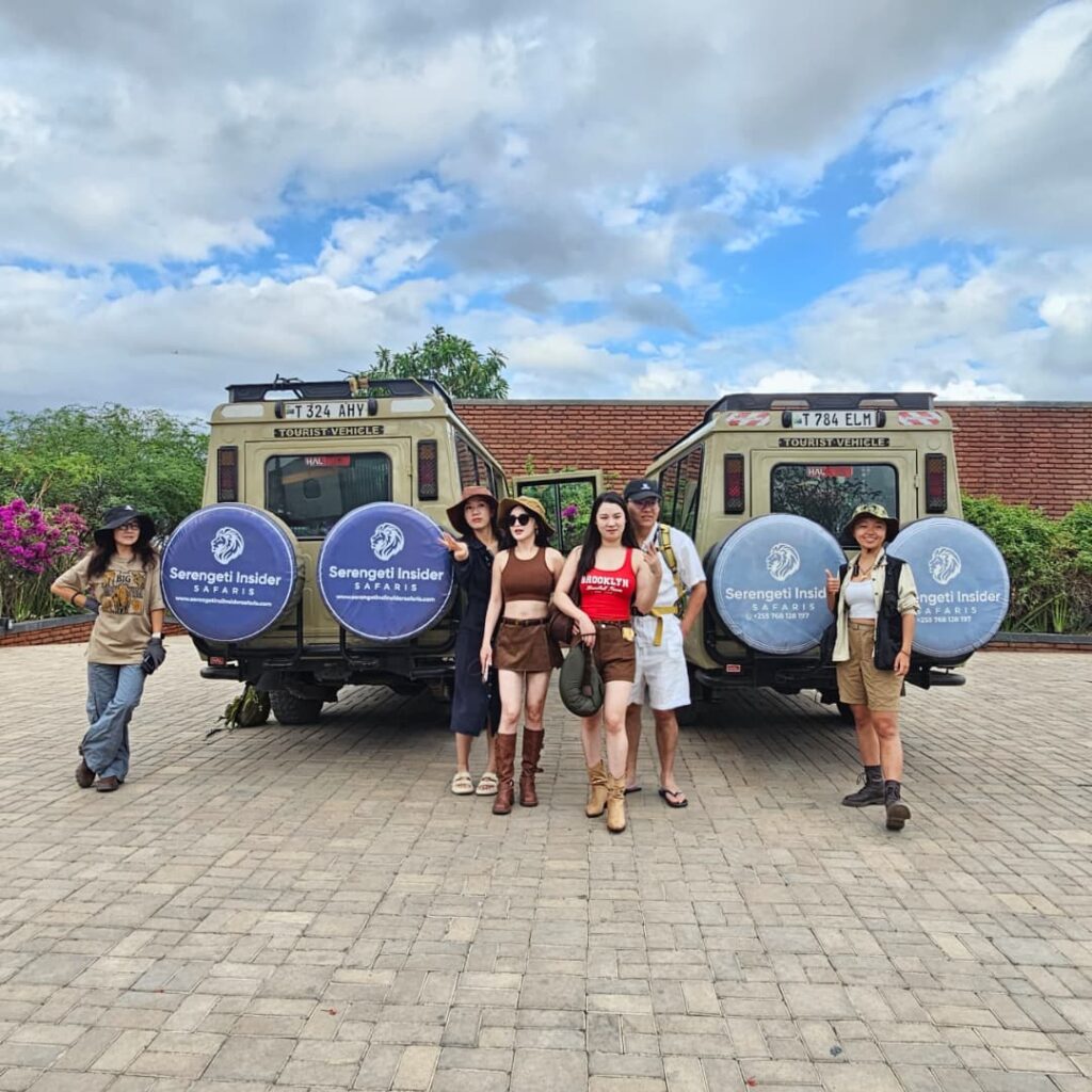 Tourists standing outside safari vehicles at Suricata Boma Lodge in Tanzania.